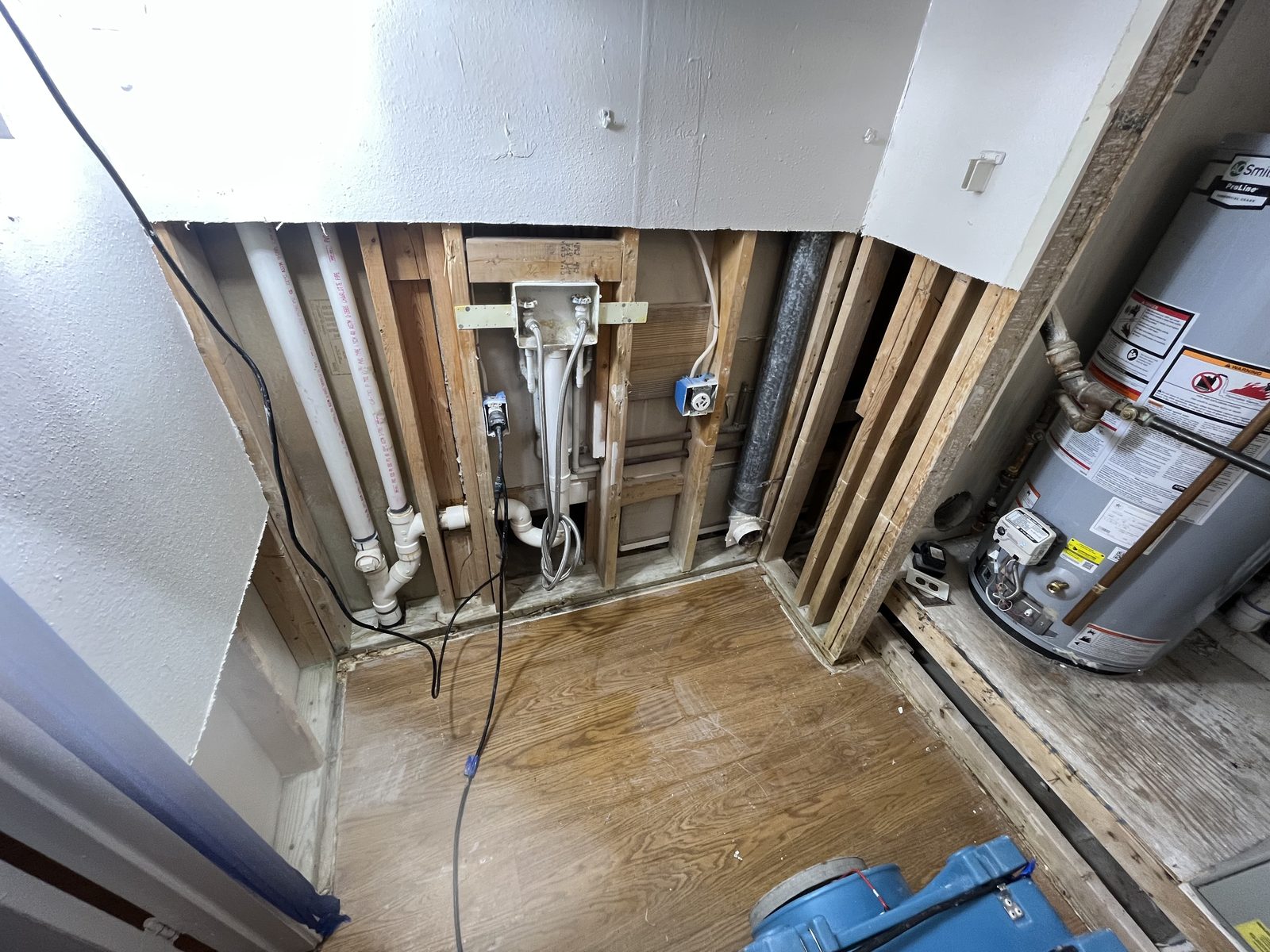 Utility closet gutted with exposed pipes and framing